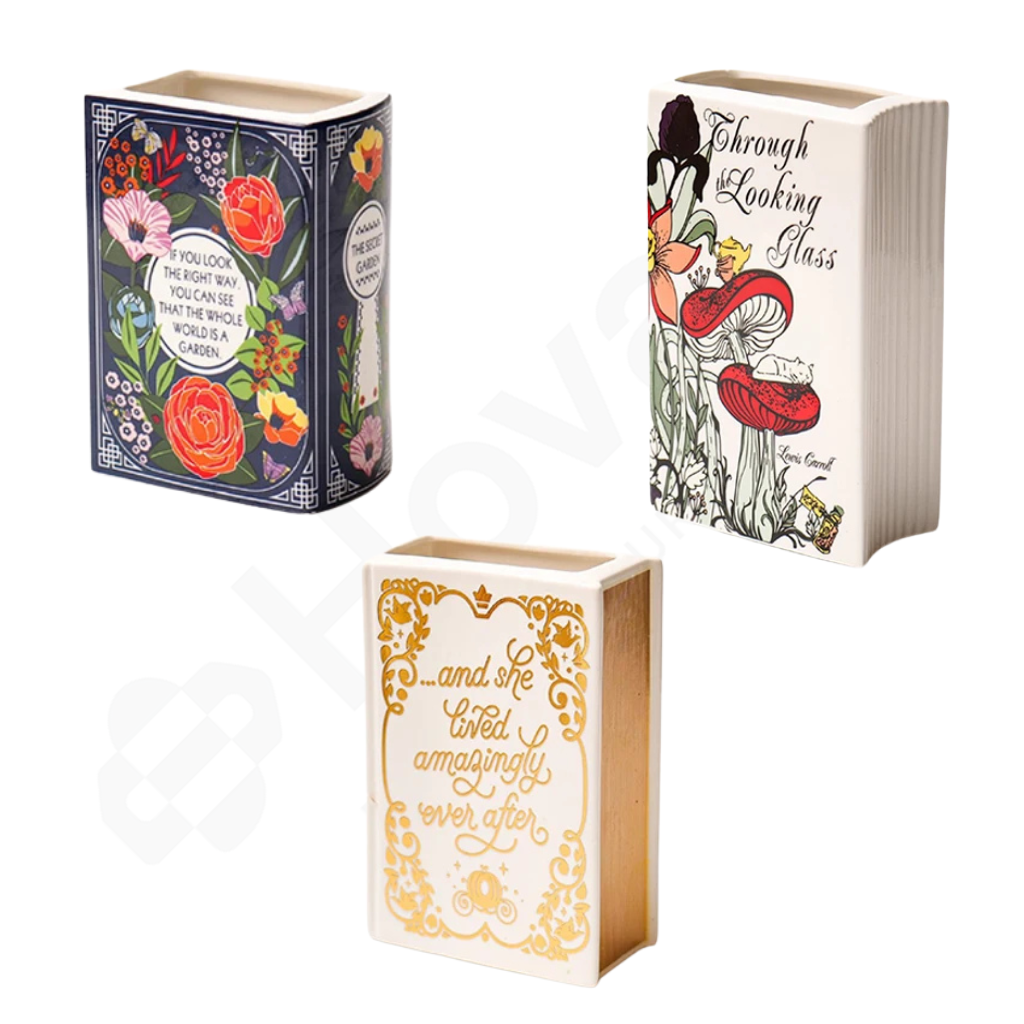 Three decorative book-shaped containers with floral and literary designs on a white background.