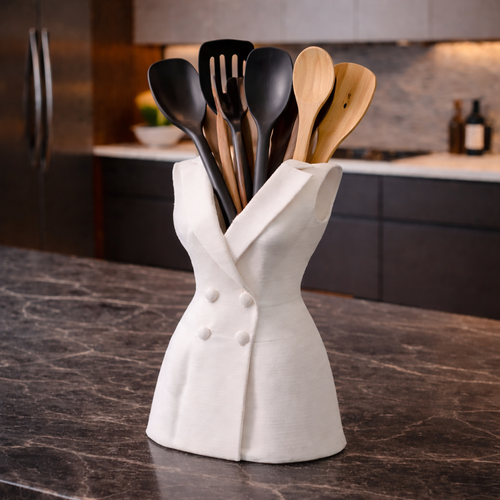 White chef's hat utensil holder with black and wooden spoons on a kitchen counter.