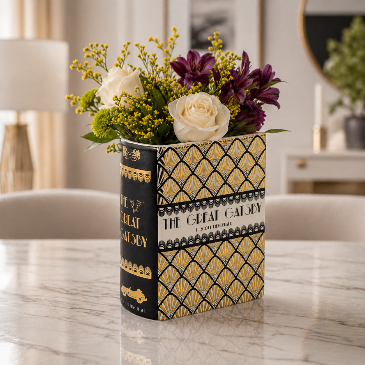 Floral arrangement in a decorative container with 'The Great Gatsby' design on a marble surface.