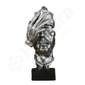 Metallic sculpture of a head with a turban on a white background