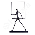 Black abstract sculpture of a figure holding a rectangular mirror on a white background